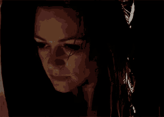 a close up of a woman 's face with a tear running down her eye .