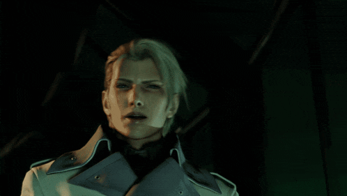 a man with blonde hair and a white coat stands in a dark room