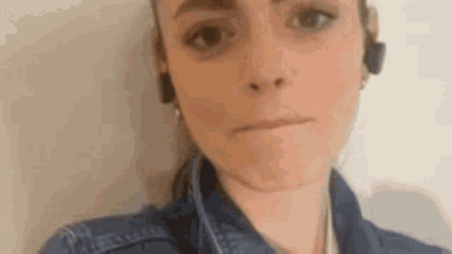 a woman in a denim jacket is making a funny face .
