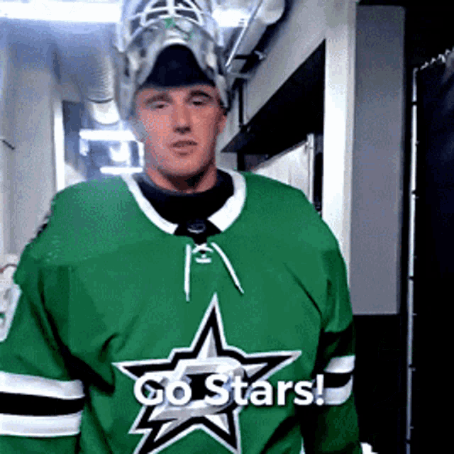 a hockey player wearing a green jersey with a star on it says go stars