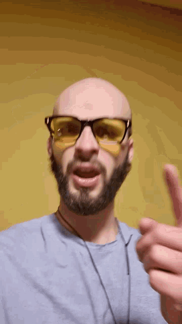 a bald man with a beard is wearing yellow sunglasses