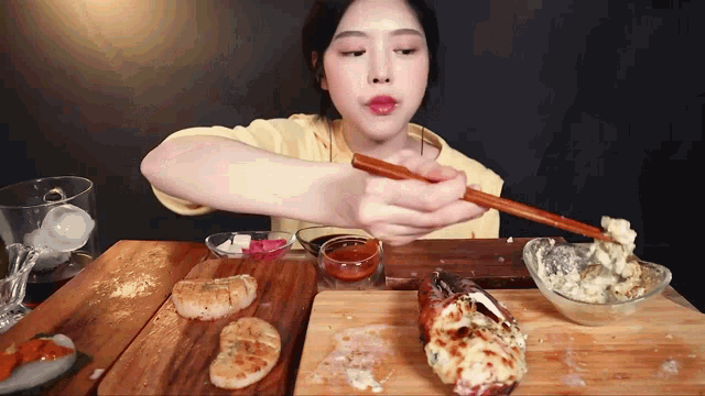 a woman is holding chopsticks over a cutting board with food on it
