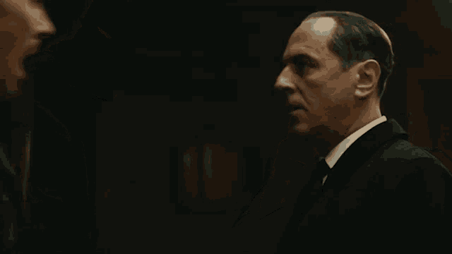 two men in suits and ties are talking to each other