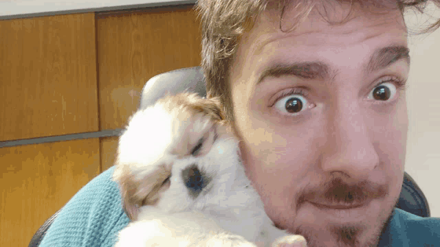 a man with a beard is holding a puppy in his arms