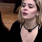 a woman wearing a black sweater and a black necklace is looking at herself in a mirror .