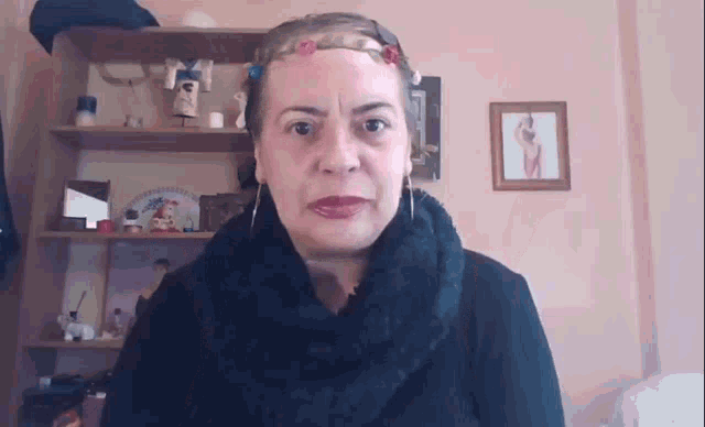 a woman wearing a black scarf and earrings is standing in front of a bookshelf .