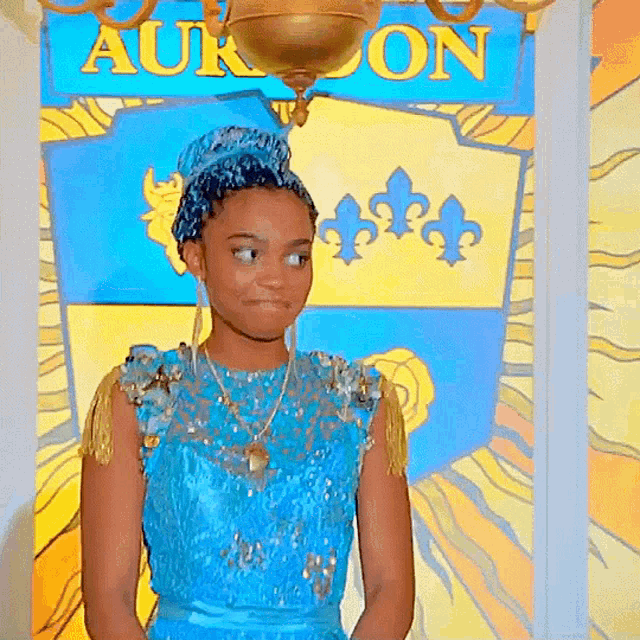 a girl in a blue dress is standing in front of a sign that says auron