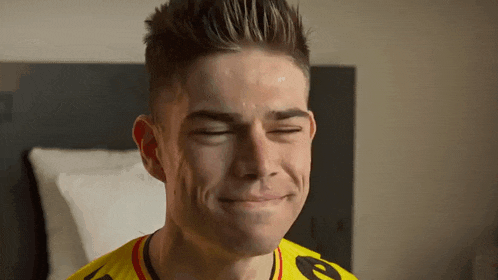 a man wearing a yellow shirt with the letter e on it is making a funny face