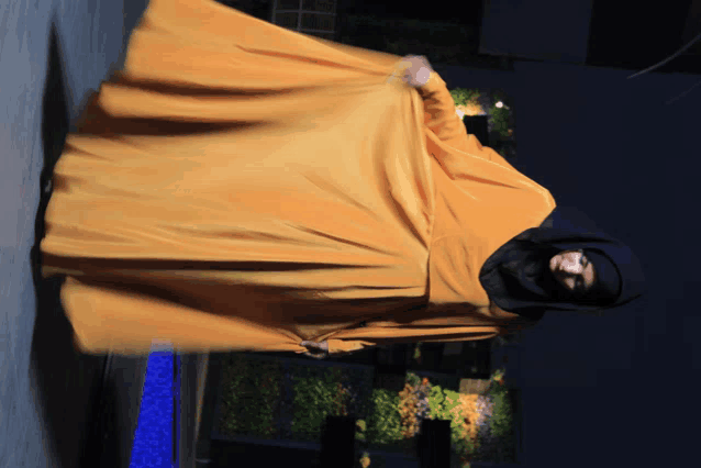 a woman in a black hijab and a long yellow dress