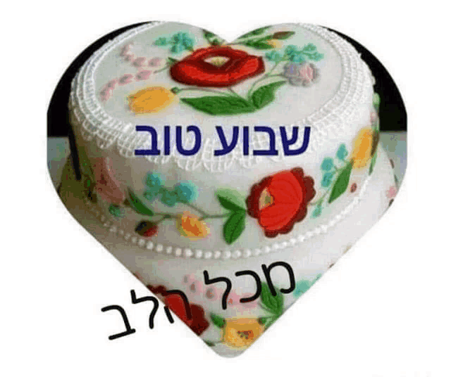 a heart shaped cake with flowers on it and the words in hebrew written on it