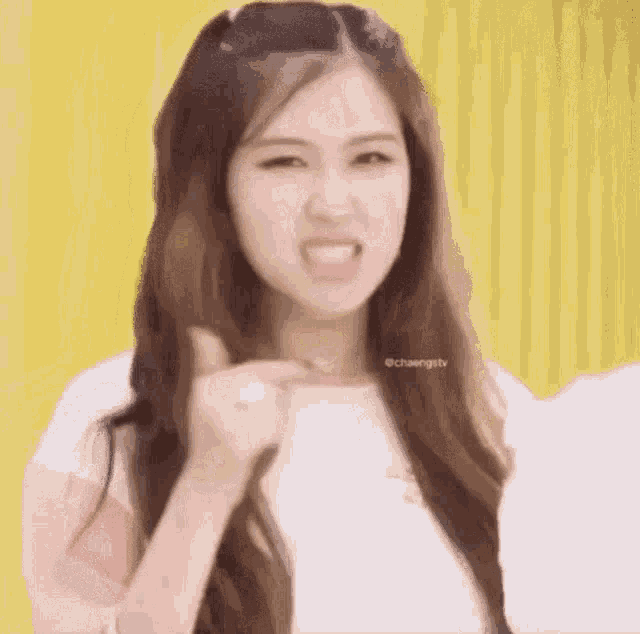 a girl with long hair is pointing at the camera with her finger .