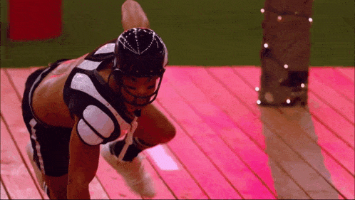 a football player wearing a helmet and shorts stands on a pink deck