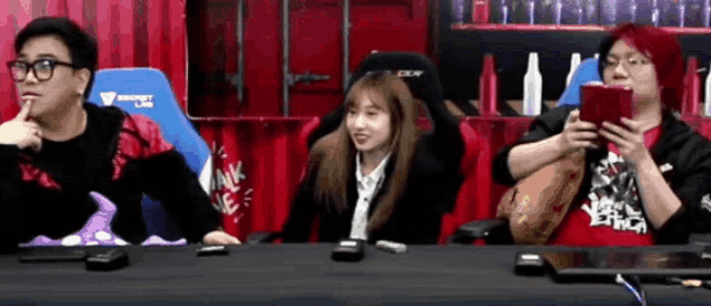 three people are sitting at a table and one of them is wearing a shirt that says ' secret lab '