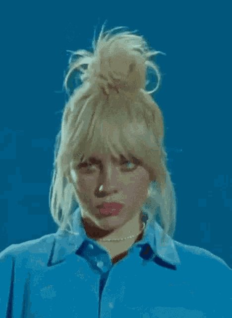 a close up of a woman 's face with blonde hair and blue eyes wearing a blue shirt .