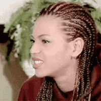 a woman with braids is smiling and wearing a red hoodie .