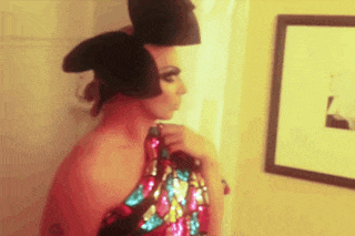 a woman in a sequined dress is standing in front of a picture on the wall