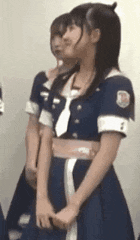 a girl in a blue dress and tie is standing next to another girl in a blue dress .