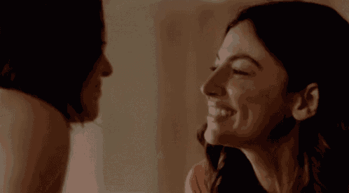 a couple of women are smiling at each other and looking at each other .