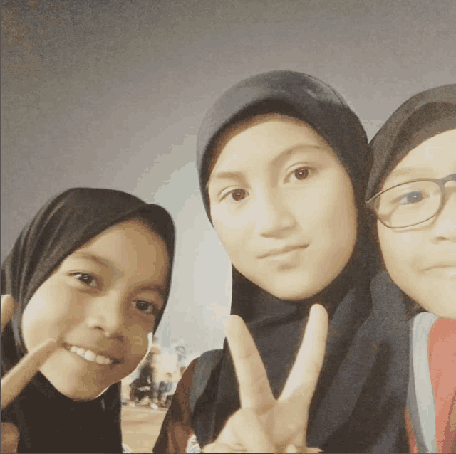 a girl in a hijab giving a peace sign