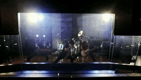 a group of people playing instruments on a stage behind a glass barrier