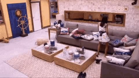 a woman is standing in a living room with a couch and two coffee tables