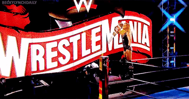 a woman in a wrestling ring in front of a wrestlemania banner