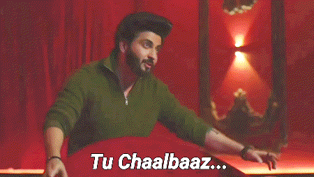 a man in a green shirt is standing in front of a red curtain with the words tu chaalbaaz written on it