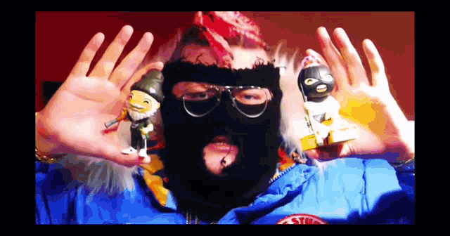 a man wearing a ski mask and glasses is holding two toys