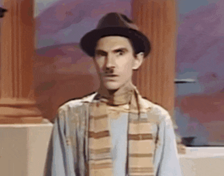 a man wearing a hat and a scarf is standing in front of a wall .