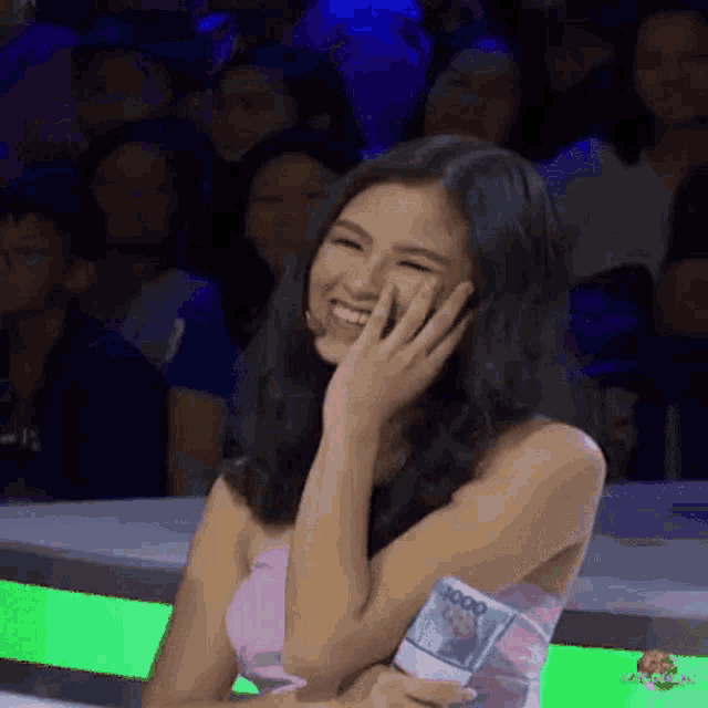 a woman is laughing while holding a stack of money in her hand