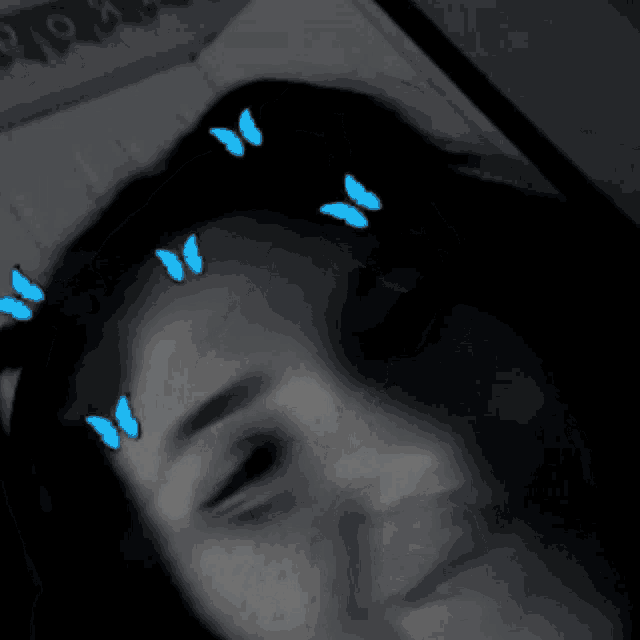 a black and white photo of a woman with blue butterflies in her hair