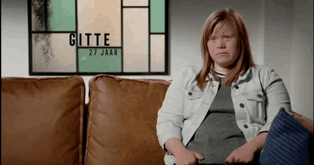 a woman sits on a couch in front of a stained glass window that says gitte 27 jaar