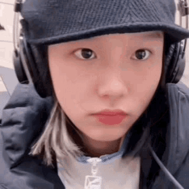 a girl wearing headphones and a hat is making a funny face .
