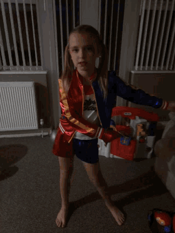 a little girl in a cheerleader costume is playing with a toy fire truck
