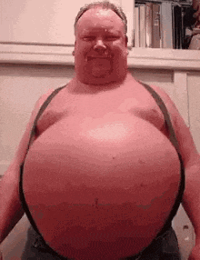 a man with a very large belly is wearing suspenders .