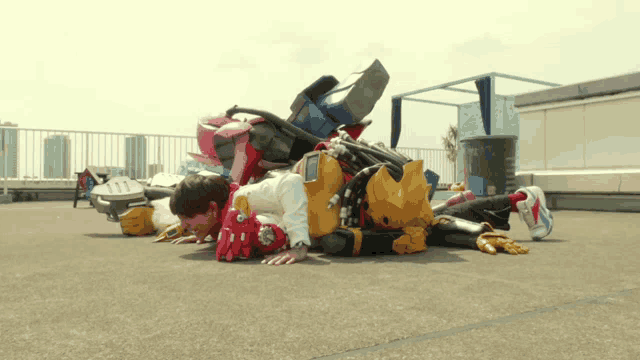a bunch of robots are laying on the ground and one of them is wearing a red helmet