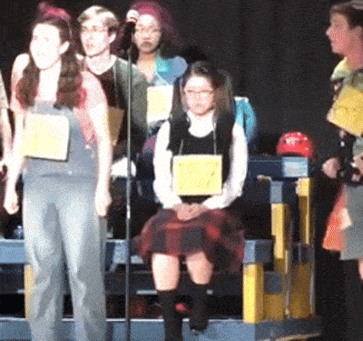 a girl in a plaid skirt is wearing a yellow tag that says ' elizabeth ' on it