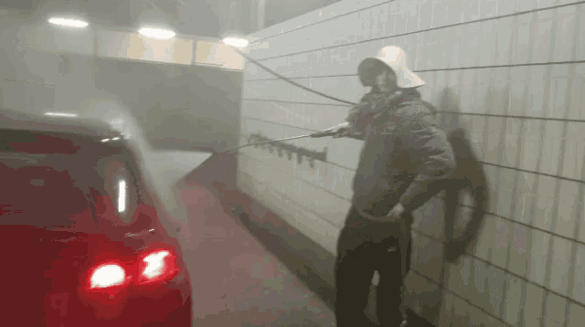 a man wearing a white hat is washing a car