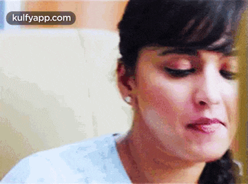 a close up of a woman 's face with her tongue out and a white shirt on .