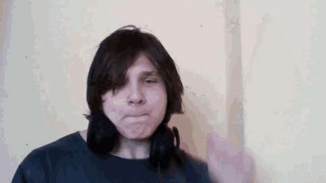 a young man wearing headphones and a black shirt is making a funny face .