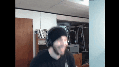 a man wearing headphones and a black beanie looks at the camera