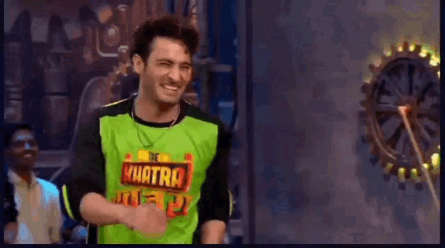a man wearing a green and black shirt with the word quatra on it is smiling .