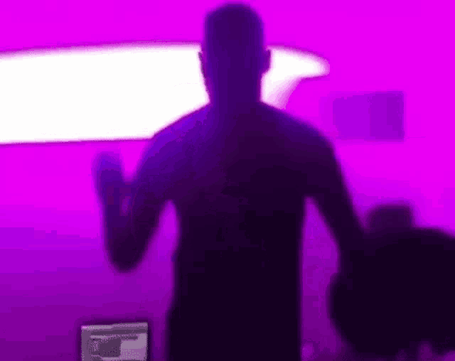 a silhouette of a man is dancing in front of a purple background .