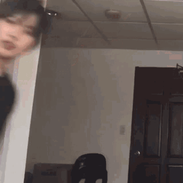 a blurry picture of a person standing in a room with a cardboard box in the corner