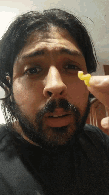 a man with a beard is holding a piece of corn in his hand
