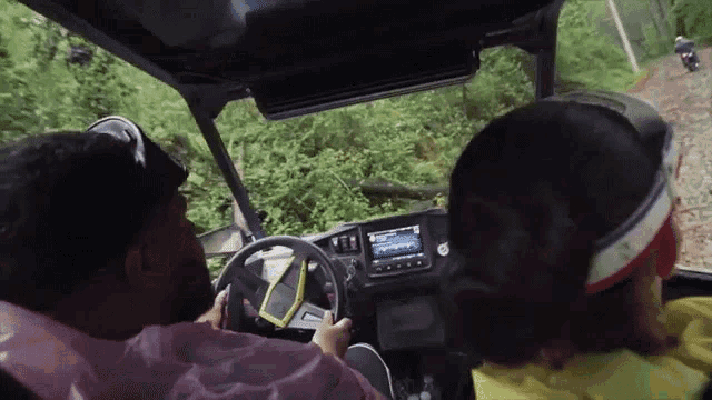 a man and woman are driving a vehicle on a trail