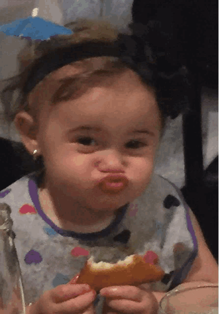 a little girl making a funny face while eating a piece of food