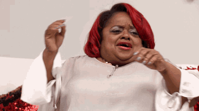 a woman with red hair and white nails is making a face