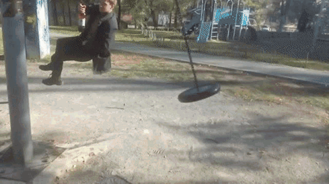 a person is sitting on a swing in a park