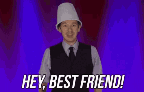 a man wearing a white hat and a vest is waving his hand and saying hey , best friend .